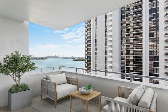 Balcony view of high-rise buildings and water body in the background.