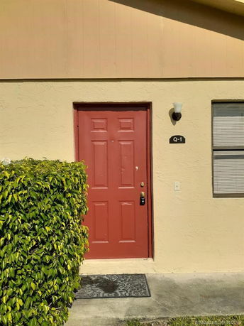 Front view of a building with a red door and a light fixture.