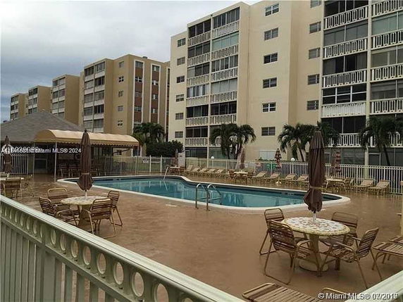 Outdoor pool area surrounded by multi-story apartment buildings.
