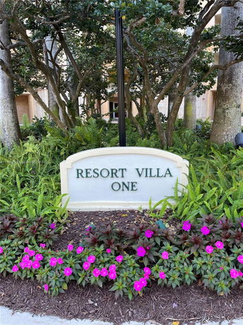 Entrance sign for Resort Villa One surrounded by trees and flowers.