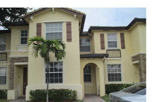 Front view of a two-story house with arched entrance and decorative shutters.
