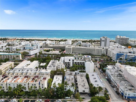 Aerial panoramic view of a coastal cityscape with buildings and ocean in the background.