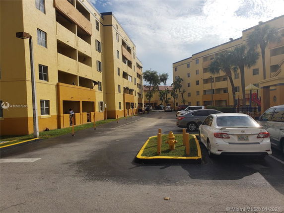 Outdoors view of a multi-story residential building with a parking area.