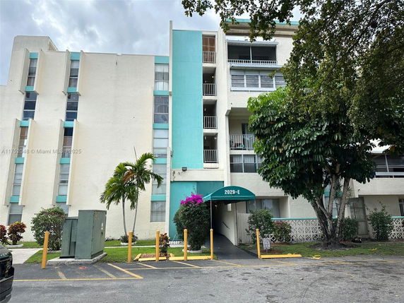 Front view of a multi-story residential building with balconies and a central entrance.