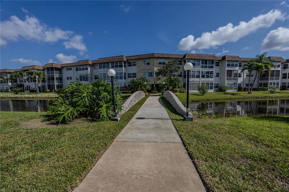 Front view of a multi-story residential building with a walkway and bridge leading to the entrance.