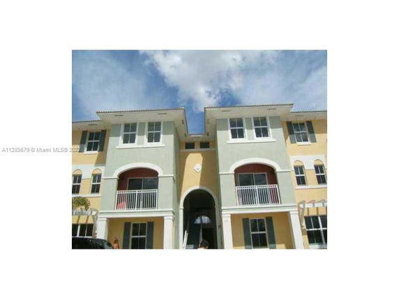 Front view of a three-story residential building with arched entrances and balconies.