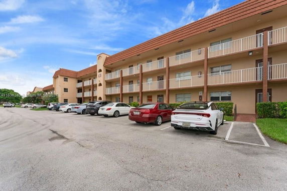 Multi-story apartment building with outdoor parking area in front.