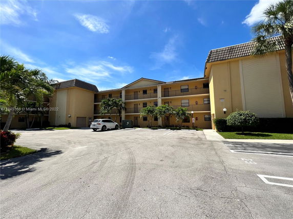 Front view of a multi-story residential building with parking area.
