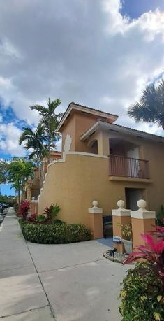 Front view of a multi-story residential building with balconies and a staircase.