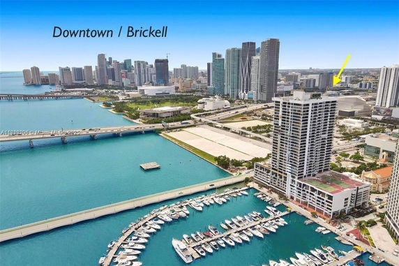 Aerial view of a coastal cityscape with a high-rise building and marina.