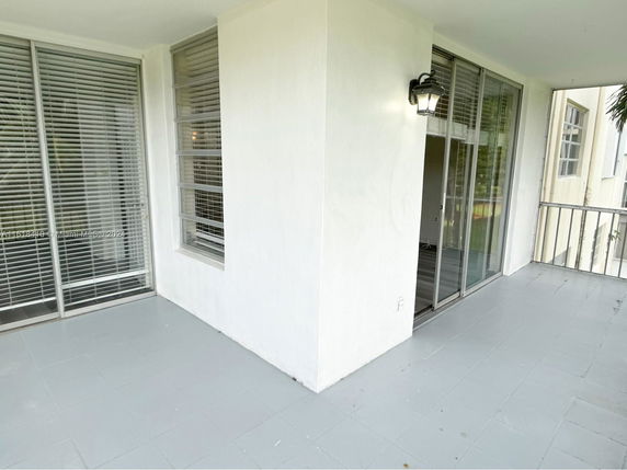 View of a balcony area with sliding glass doors and windows with blinds.