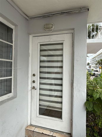 Front view of an entrance door with striped glass and outdoor lighting.