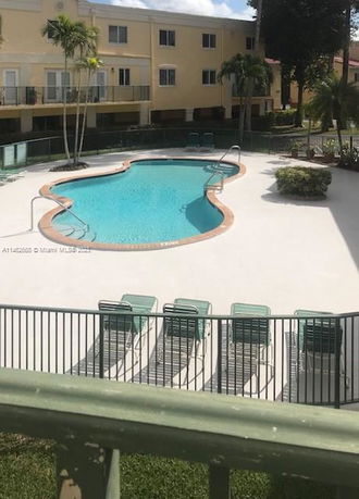 Outdoor swimming pool area with lounge chairs and fenced surroundings.