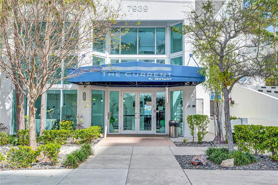 Front view of a building with a blue awning labeled 'The Current by Sextant'.