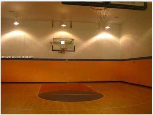 Indoor basketball court with a hoop and marked floor.