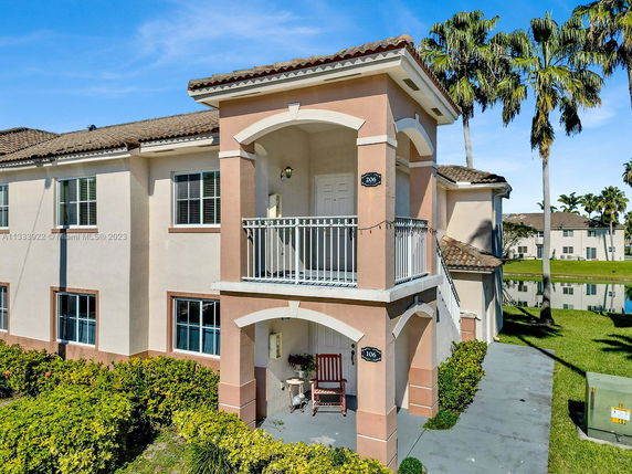 Front view of a two-story residential building with a small balcony and arched entrance.