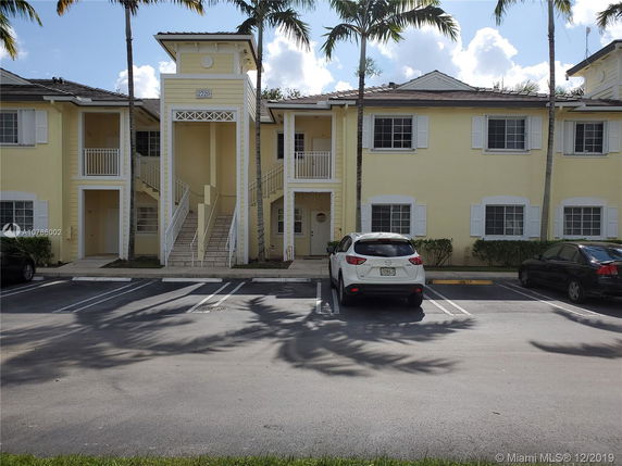 Front view of a two-story apartment building with exterior stairs and parking area.
