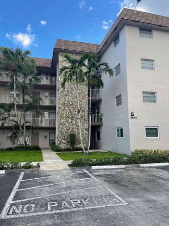Front view of a multi-story residential building with balconies and a stone facade.