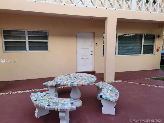 Front view of a building entrance with a decorative table and benches.
