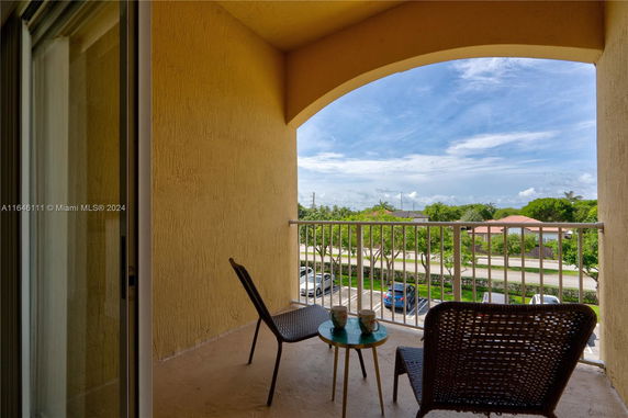 Balcony view with chairs overlooking surrounding area with trees and houses.