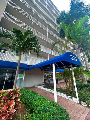 Front view of a multi-story building with balconies and a blue entrance awning.