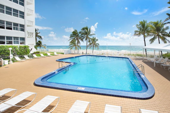 Outdoor swimming pool area with lounge chairs and ocean view.