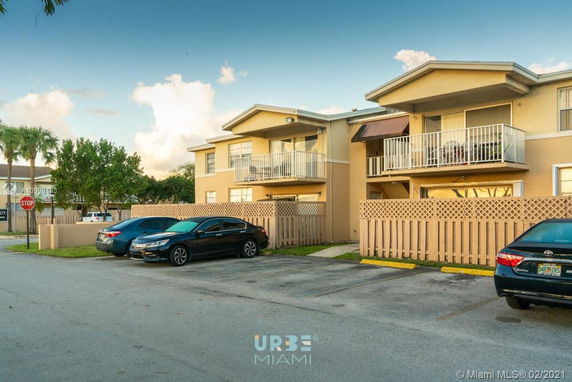 Front view of residential building with parked cars and balconies.