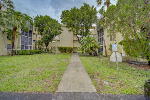 Front view of a multi-story apartment building with surrounding trees and greenery.