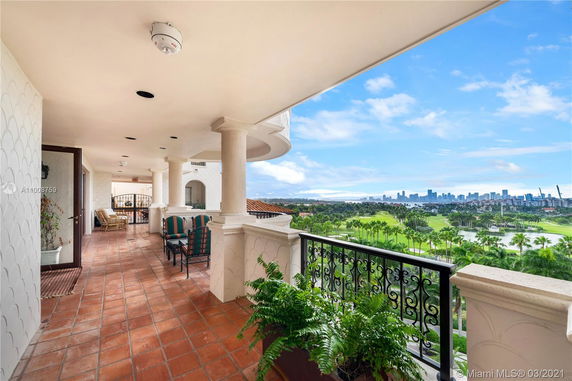 Outdoor balcony with seating, offering a scenic view of a golf course and city skyline in the background.