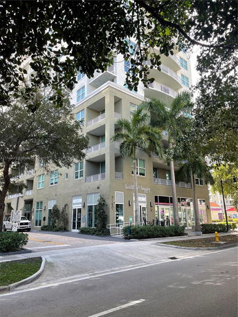 Front view of a multi-story building with balconies and ground-level commercial spaces.