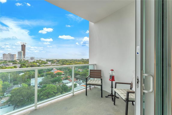 Balcony view overlooking a cityscape with distant buildings and greenery.