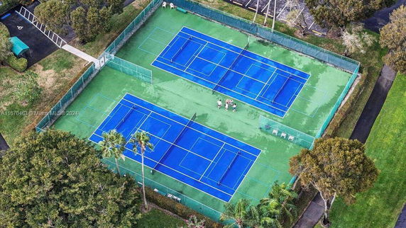 Aerial view of two blue tennis courts surrounded by green fencing.