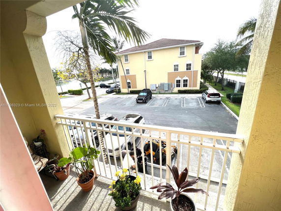 View from a balcony overlooking a parking area and adjacent buildings