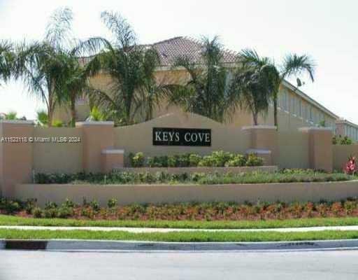 Front view of the Keys Cove residential complex with a sign and landscaping in front.