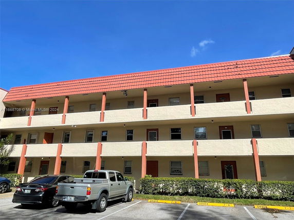 Front view of a multi-story residential building with parking area.