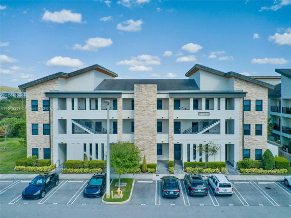 Front view of a multi-story apartment building with parking spaces.