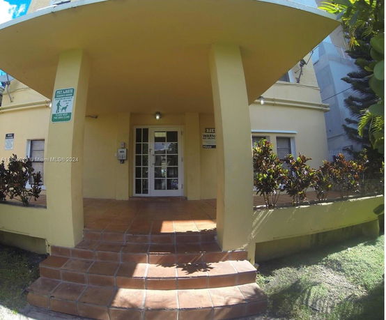 Front view of a two-story building with a covered entrance and tiled steps.