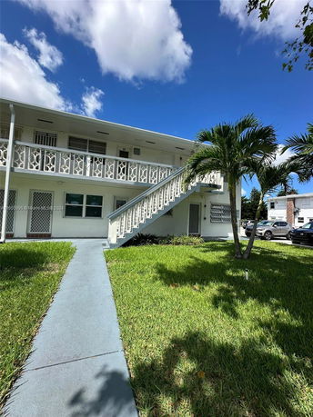 Front view of a two-story building with an external staircase and decorative railing.