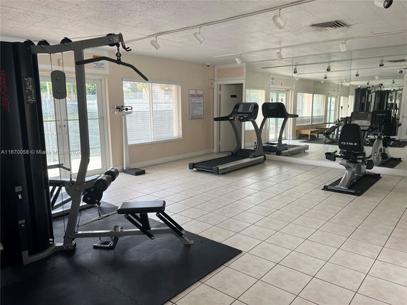 Interior view of a gym area with exercise equipment and mirrors.