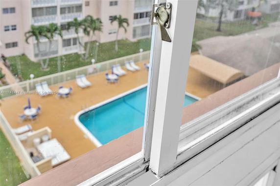 View from a window overlooking a swimming pool area with lounging chairs.