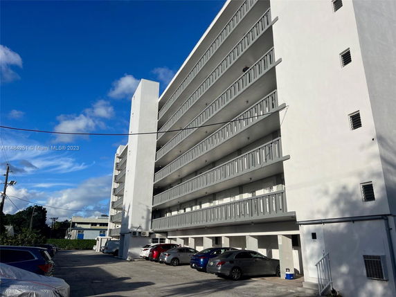 Side view of a multi-story apartment building with parking area.