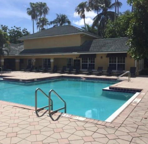 Outdoor swimming pool with a building in the background.