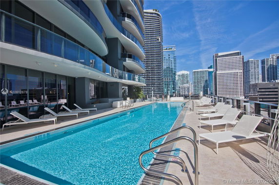 Rooftop view with a swimming pool and lounge chairs on a high-rise building.
