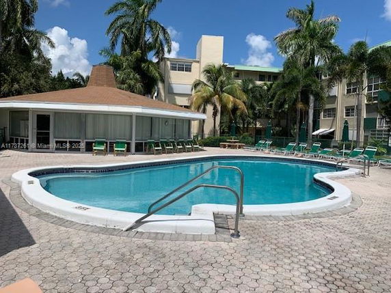 Outdoor swimming pool area with lounge chairs and surrounding palm trees.