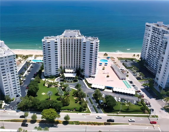 Aerial view of a beachfront residential complex with high-rise buildings and a swimming pool area.