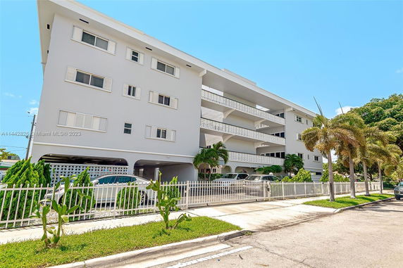 Front view of a multi-story building with a parking area on the ground level.