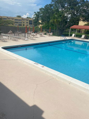 Outdoor swimming pool with surrounding lounge chairs and umbrellas.
