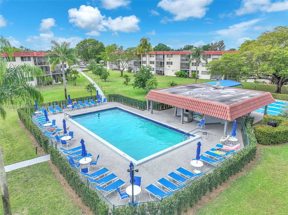 Outdoor swimming pool area with lounge chairs and umbrellas.