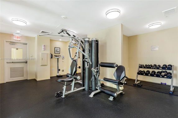 Interior view of a gym area with fitness equipment and dumbbells.
