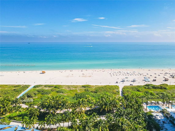 Wide-angle view of a beach with clear blue water and a sandy shore, seen from an elevated perspective.